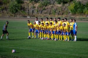 Иван Станчев направи равносметка за 2025 г. във Волов-Шумен 2007 Президентът на Волов-Шумен 2007 Иван Станчев направи обзор на 2025 година за тима. Шуменци завършиха на трета позиция през кампания 2024/25 в Североизточната Трета лига след добра пролет, а тази есен приключиха на четвъртата позиция с изоставане от 7 точки от топ 3. Какво сподели Станчев за ситуацията в клуба и нивото в групата? Какви теми засегна още президентът на "жълто-сините"? Отговорите в интервюто с него, направено специално за официалния сайт на Волов-Шумен 2007, дело на проекта Дигитален Спорт на bookmaker-ratings.bg. - С оглед на представянето през втората половина на миналия сезон и първата част на този, каква оценка бихте дали за изявите на отбора през 2025 година? - Моята лична оценка е, че представянето ни е добро. Ако погледнем втория полусезон на миналата кампания, тогава спечелихме доста мачове и статистически завършихме статистически доста добре. Реално, ако се гледа само този период, сме втори в класирането. Можеше и буквално да си завършим втори там. Имаше и трудни, инцидентни срещи. Ако сравним първия полусезон на настоящето първенство с първия полусезон на миналото, балансът е почти същият. Тогава завършихме с 9 победи, 2 равенства и 4 загуби, а сега сме с 10 победи, 2 равенства и 4 загуби. Картината е сходна, но тази есен Лудогорец III се представят доста успешно и са пред нас в класирането. Миналата година завършихме есенния полусезон на второ място, но с мач повече от Черноломец (Попово), с който после ни изпревари. С оглед представянето сме доволни. Имаше мачове, в които можехме да вземем повече, но не успяхме. Понякога заради наши грешки, друг път заради силното ни желание за победа, което ни изигра лоша шега. Надяваме се това да ни послужи като урок за пролетния полусезон – да подхождаме с по-малко напрежение и очаквания. Когато напрежението е по-малко, резултатите са по-добри. Напрежението сковава футболистите и желанието идва в повече. Това води до грешки. - Чисто статистически има сякаш спад в защита и подобрение в атака, където се открояват някои фигури. Това така ли е? Ще се работи ли върху подобряване на защитата на отбора? - Да, това е нещо, което ясно забелязваме. Защитата има пропуски, но в съвременния футбол не можем да разделим отбора на зони. Отговорност носят всички – от нападателите до защитната линия. Когато сме в защита, всички трябва да защитават, а когато сме в атака – всички да участват. Трябва да работим в тази посока да не допускаме толкова много голове. На това ще наблегнем по време на зимната подготовка. - В сравнение с пролетните резултати имаше мачове тази есен, в които допуснахте много попадения, но все пак спечелихте. Защо се получава така, че атаката трябва да компенсира? - Да, точно това се случи този полусезон. Обикновено на нас ни вкарват голове и ние тръгваме да обръщаме резултата. Допускаме лесни голове, особено в първите полувремена, и трудно влизаме в мачовете. Влезем ли в мача, можем да обърнем резултата за 10-15 минути. Но доста по-трудно се играе, когато трябва да се обръща негативен резултат. Точно затова трябва да работим и в тази насока по време на предсезонната подготовка. - В такъв случай представянето в атака ли е причината да се даде добрата оценка за представянето на отбора? - Да, смея да твърдя, че имаме добри нападатели. Митко Игнатовски и Румен Николов са вкарали повече от половината голове, от всички 40, те са отбелязали 23. Много голям плюс за нас е, че реализираме голяма част от създадените положения. Въпреки всичко искаме да бъдем още по-ефективни в атака. Част от добрата ни голова разлика идва от няколко мача с убедителни победи, например 5:0 над Рилци и над Фратрия, срещу Дончево вкарахме четири гола. Тези неща са добри, като цяло. Имаме добри изпълнители в атака, но в действителност не трябва да допускаме толкова голове в нашата врата. В крайна сметка по-важно е да победиш с 1:0 или с 1 гол повече, но важна е победата. - Можем ли да кажем, че ако се подобрят тези неща, Волов-Шумен 2007 има шанс да се изкачи по-напред в класирането, или подобрените при конкуренцията ще попречи на тима да прогресира в сравнение с миналия сезон? - Ще се борим, разбира се, не сме се отказали. Ще бъде трудно, защото ще се борим с отбори, които наистина показват доста голямо израстване, но е възможно да постигнем резултати, възможно е да ги победим тези отбори. Всичко зависи от нас – добра зимна подготовка, добра мотивация по време на мачовете и всичко останало е в нашите ръце. Радваме се, когато играем със силни отбори. Проблемът през есенния полусезон беше, че не успяхме да вземем точки срещу силните отбори, които са пред нас в класирането. Даже и срещу отборите, които са след нас не записахме победи. Срещу Бенковски (Исперих) направихме трудно равенство, а от Черноломец (Попово) загубихме. Ако искаме да се изкачим по-напред в класирането, трябва да побеждаваме водещите отбори. Ако побеждаваме само отборите в последната четворка, ще ги побеждават и голяма част от отборите в челото. Няма как да стане да не печелим срещу водещите отбори и да се изкачим на по-предно място. Това е директна битка между тях и нас. - Има ли вдигане на качеството в групата с оглед това, което се случва не само в отбора на Черноморец (Балчик), определян от мнозина за най-силния в групата, но и спрямо прогреса в Исперих и Дончево? - Аз също споделям мнението, че Балчик е най-силният отбор в групата в момента. Качеството на отборите в групата е доста по-високо. Или по-скоро са доста изравнени силите. Освен първите три тима в класирането можем да продължим с Волов-Шумен, с Исперих, с Попово, няма да изключа и Дончево, и Силистра. Това са отбори, които могат да победят всеки и винаги се борят за предни места. Не трябва да изключваме и дублиращите отбори на Черно море и Спартак (Варна). Всеки може да победи всеки. Доста е високо нивото на нашата група тази година, в сравнение с миналата година. Тогава се открояваха няколко тима, на които другите отстъпваха. Сега има повече отбори на високо ниво, което прави мачовете по-интересни.