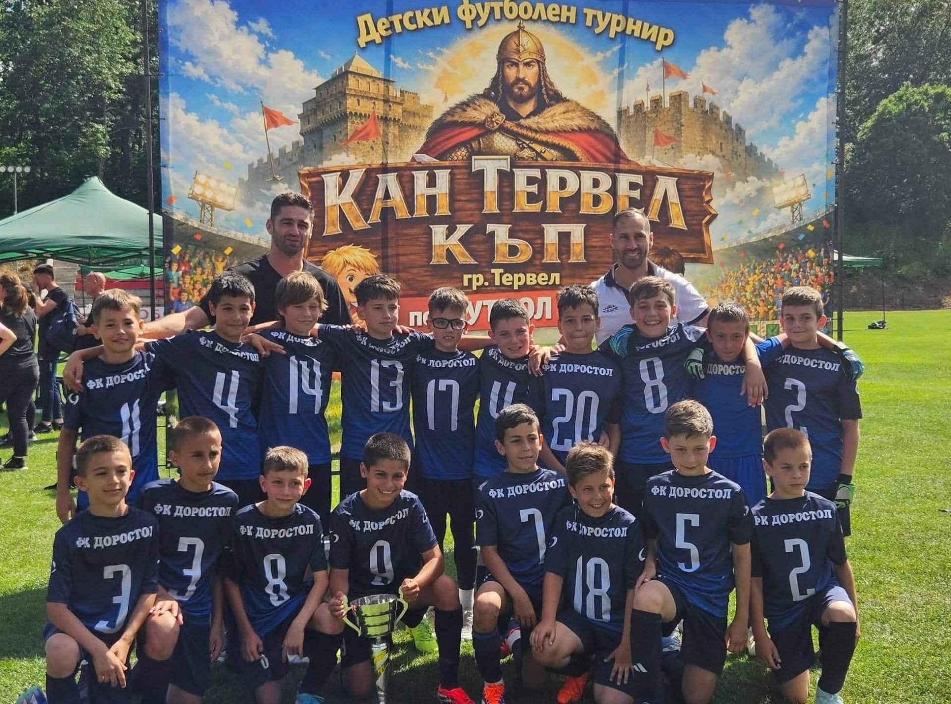 Децата на Доростол триумфираха на "Кан Тервел Къп" Децата на Доростол Силистра в две възрастови групи спечелиха второто издание на турнира „Кан Тервел Къп“ в град Тервел. На 30-ти и 31-ви май силистренският клуб бе представен от наборите родени през 2015 и 2016 година (Футбол-7), както и от набор 2017/18 (Футбол-5). И в двете възрастови групи младите футболисти завоюваха златните медали. Наградите и купата за шампиони им бяха връчени от специалните гости на турнира Петър Занев - директор на Академия ЦСКА и футболист с впечатляваща кариера в ЦСКА, Селта Виго и националния отбор на България, и Даниел Димов - дългогодишен футболист на Черно море и Левски. Напомняме, че в първото издание, проведено през миналата година, Доростол също спечели убедително турнира при децата, родени през 2013 и 2014 година. Този турнир е много повече от мачове – той е усмивки, приятелства, първи стъпки към големите мечти и вяра, че всичко е възможно. Благодарности към организаторите от ФК Септември (Тервел) за отличните условия за футбол, перфектната организация и топлото отношение.