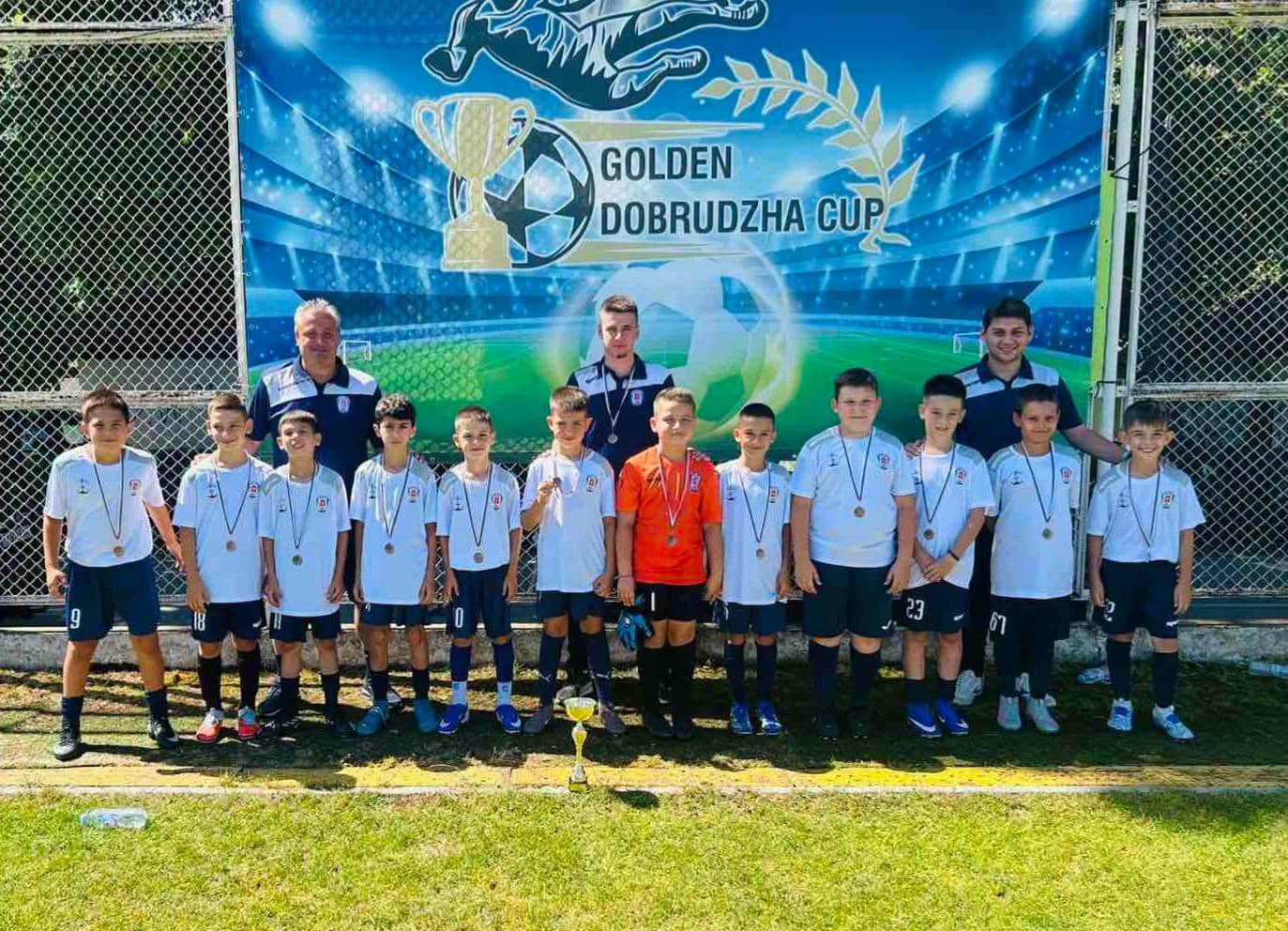ФК Доростол Силистра с сребро и бронз от Golden Dobrudzha Cup Младите таланти на ФК Доростол Силистра постигнаха отличен резултат на международния детски турнир Golden Dobrudzha Cup, завоювайки сребърни и бронзови медали в две възрастови групи. Надпреварата се проведе на терените в КК Албена от 25 до 28 юни и събра отбори от България и чужбина. Футбол-5 (до 8 г.) — сребърен медал Под ръководството на треньорския екип Деян Дечев, Георги Иванов и Стоян Ангелов отборът до 8 години впечатли с характер и дисциплина и достигна финала в турнира на формат Футбол-5. В груповата фаза и елиминациите момчетата записаха убедителни победи: Добруджа (Добрич) — 5:1 Розова долина (Казанлък) — 12:0 Фортуна (София) — 3:0 Национал (София) — 5:1 Във финалния двубой отстъпиха с 1:3 на Тича (Варна) и завършиха турнира със сребърни отличия. Футбол-7 (до 9 г.) — бронзов медал Отборът до 9 години се включи в турнира на формат Футбол-7 и спечели бронзовите медали. В дебютното си участие в този формат "доростолчета" стартираха силно с победи: Добруджа — 10:1 Академия Хаджи (Румъния) — 8:2 В полуфинала отстъпиха на шампиона в тази възрастова група Национал (София), а в мача за третото място победиха Шампиони (Варна) и заеха почетното трето място. Ръководството на клуба изказва благодарности към родителите, приятелите и всички, които подкрепиха отбора от трибуните. Вашата подкрепа дава криле на децата да продължат напред!